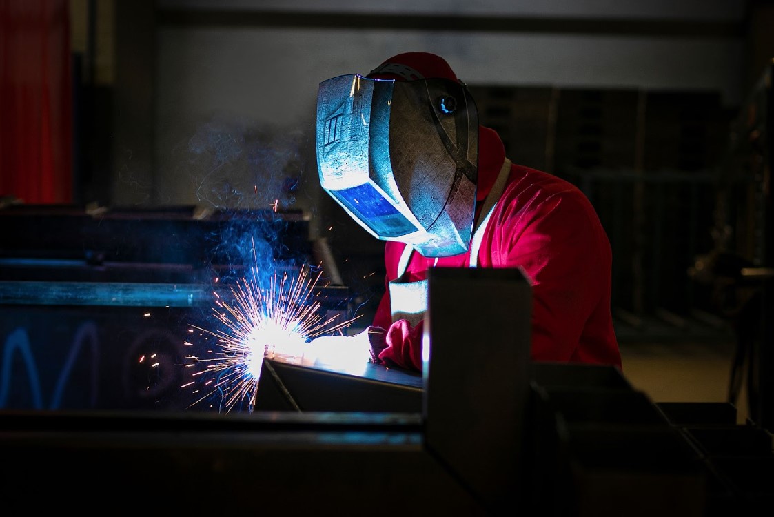 Homem trabalhando na soldagem de metal na indústria.