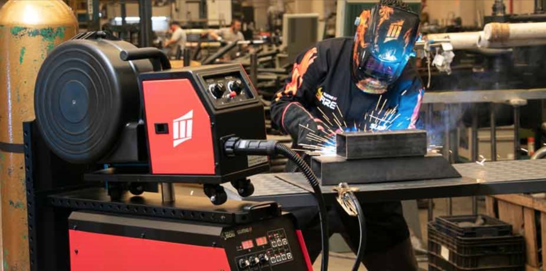 Homem trabalhando em solda de metal em indústria.